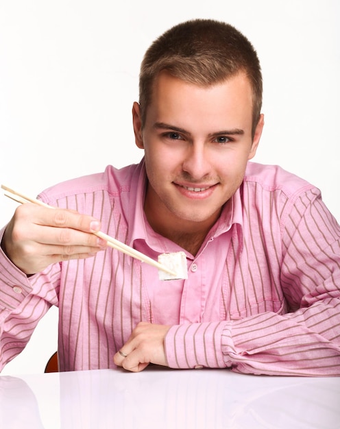 Joven sentado y sosteniendo palo con sushi