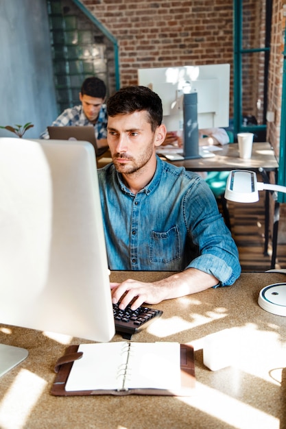 Foto joven sentado en su escritorio en la oficina