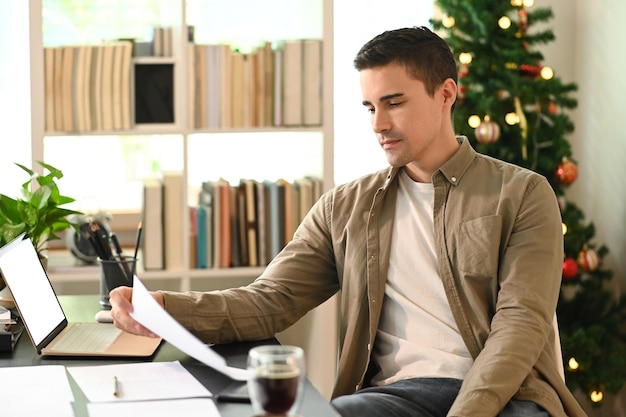 Joven sentado en su lugar de trabajo y leyendo un documento