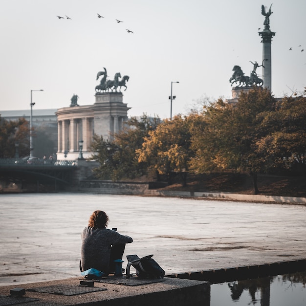 Joven sentado con su teléfono en el parque en la ciudad de Budapest, Hungría