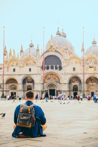 Joven sentado en el suelo mirando la iglesia de la catedral de san marcos