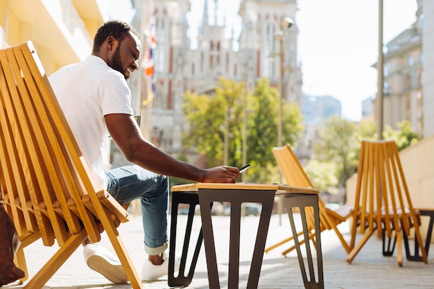 Joven sentado en una terraza y leyendo un artículo