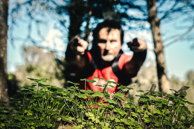 Foto joven sentado en la tierra contra los árboles