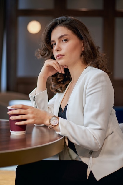 Joven seria bebiendo café en un café