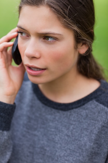 Joven seria hablando por teléfono mientras mira hacia el lado