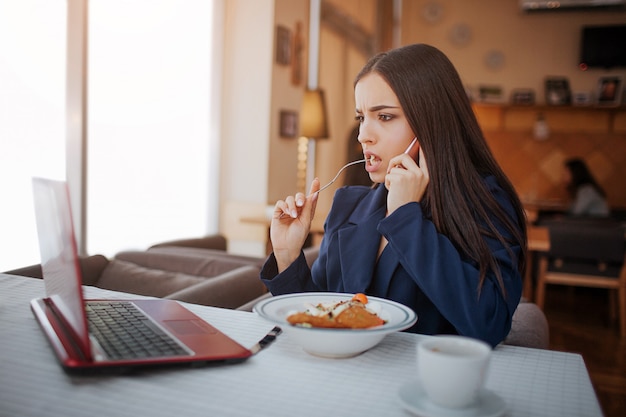 Joven seria sentarse a la mesa en el restaurante