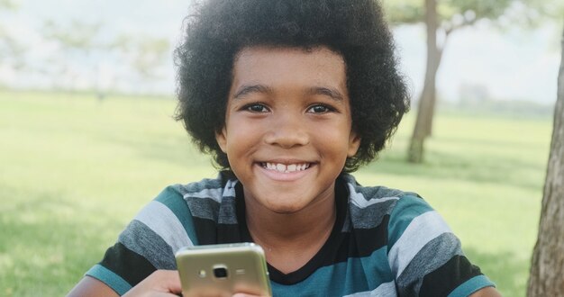 El joven se sienta en la hierba en el jardín y con smartphone.