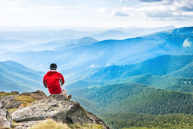 Joven se sienta y medita en la cima de la montaña