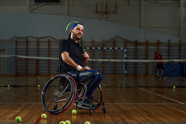 Joven en silla de ruedas jugando al tenis en la cancha de tenis en silla de ruedas