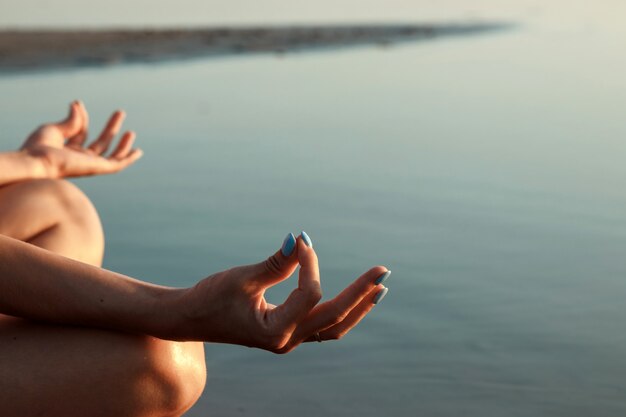 Joven silueta, yoga en la naturaleza, en un lago y hermosa puesta de sol