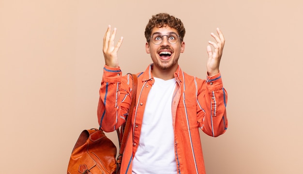 Joven sintiéndose feliz, asombrado, afortunado y sorprendido, celebrando la victoria con ambas manos en el aire. concepto de estudiante