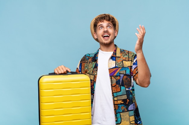 Joven sintiéndose feliz, asombrado, afortunado y sorprendido, celebrando la victoria con ambas manos en el aire