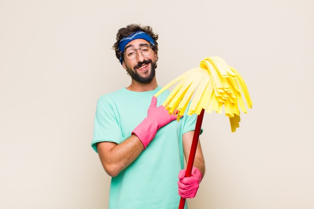 Foto joven sintiéndose feliz y enamorado, sonriendo con una mano al lado del corazón y la otra estirada al frente