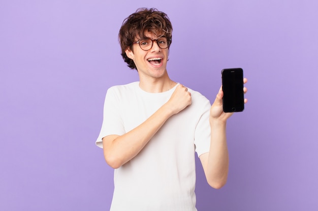 Joven sintiéndose feliz y enfrentando un desafío o celebrando y sosteniendo una celda