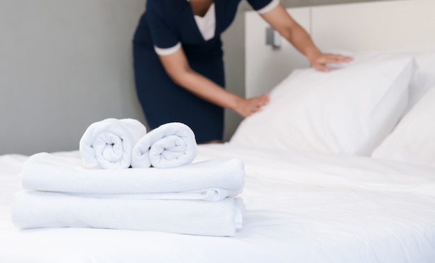 Foto joven sirvienta haciendo la cama en una habitación