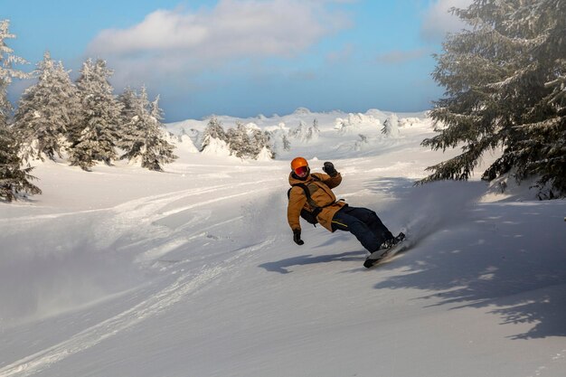 Joven snowboarder atlético con abrigo amarillo brillante cabalgando sobre splitboard salpicando nieve