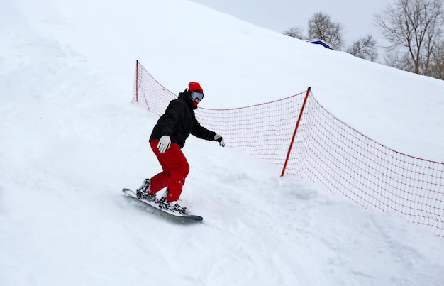 Un joven snowboarder corre por una pendiente en las montañas alpinas, deportes de invierno, recreación al aire libre
