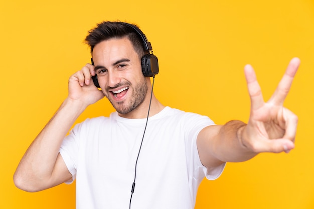 Joven sobre pared amarilla escuchando música y cantando