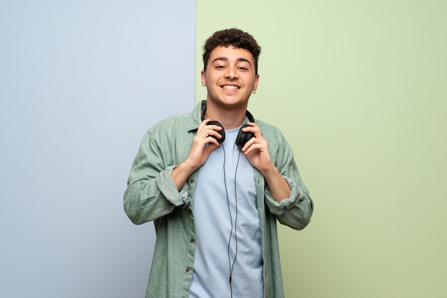 Joven sobre pared azul y verde con auriculares