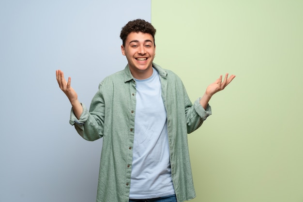 Joven sobre pared azul y verde sonriendo con una dulce expresión