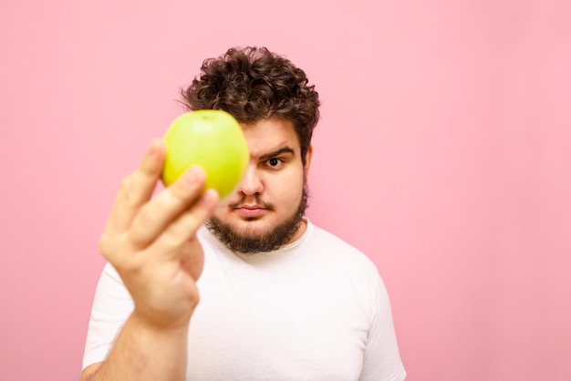 Joven con sobrepeso sostiene una manzana cerca de la cámara aislada