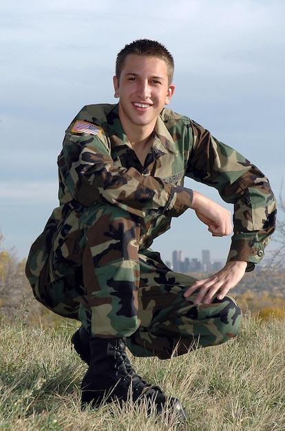 Un joven soldado norteamericano en uniforme posa en la cima de una colina
