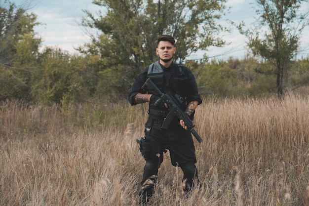 Joven soldado en uniforme negro con un rifle de asalto