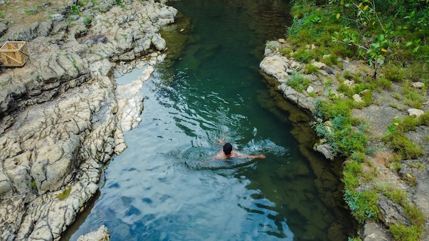 Joven solo nadando en un río limpio y hermoso