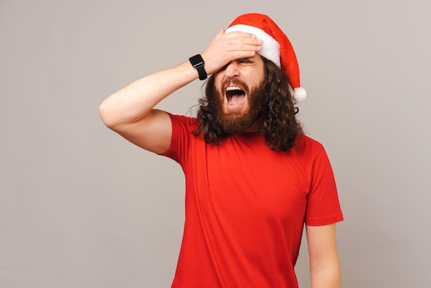 Joven con sombrero de Navidad olvidó algo y se da una palmada en la cara