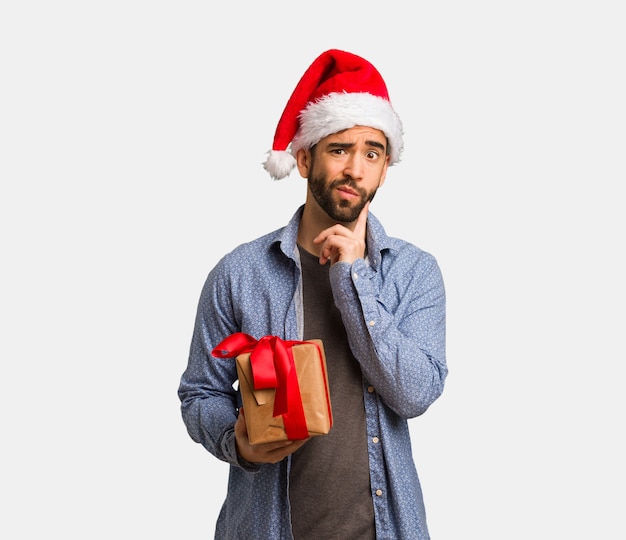 Joven con sombrero de santa dudando y confundido