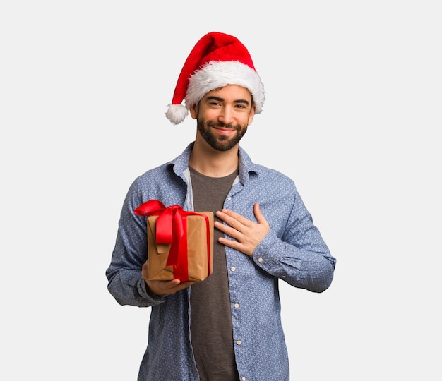 Joven con sombrero de santa haciendo una forma de corazón con las manos