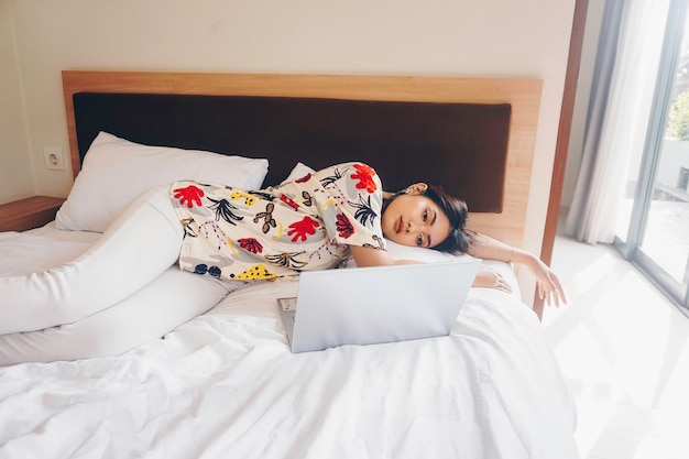 Foto una joven somnolienta bostezando mientras trabaja desde la cama