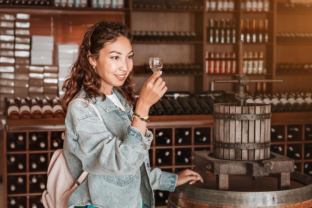 Foto una joven sonríe de alegría mientras toma un sorbo de vino blanco mientras visita una bodega