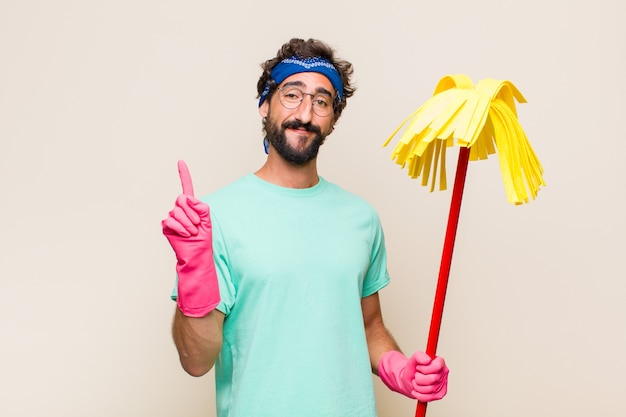 Foto joven sonriendo alegre y alegremente, apuntando hacia arriba con una mano