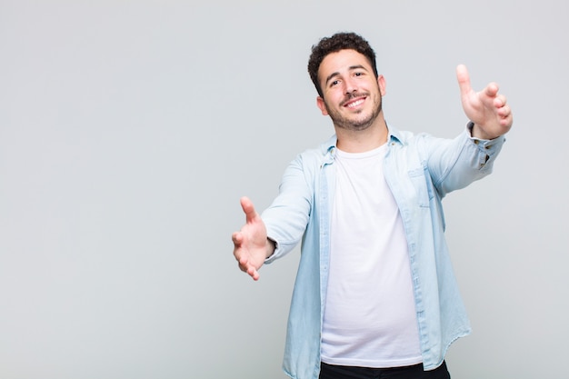 Joven sonriendo alegremente dando un abrazo de bienvenida cálido, amistoso y amoroso, sintiéndose feliz y adorable