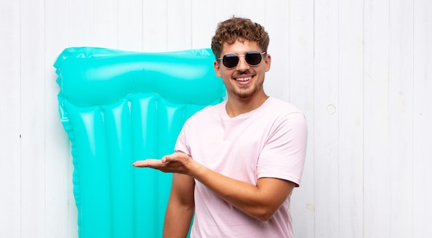 Joven sonriendo alegremente, sintiéndose feliz y mostrando un concepto en el espacio de la copia con la palma de la mano. concepto de vacaciones