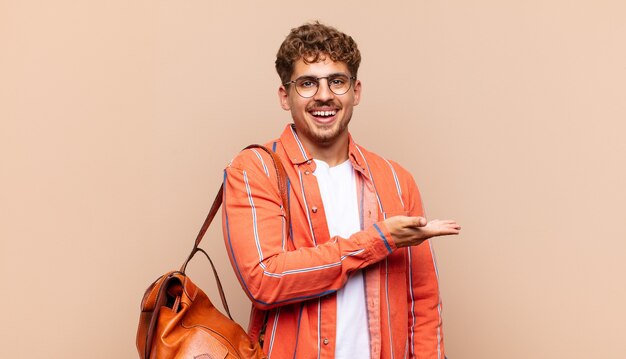 Joven sonriendo alegremente, sintiéndose feliz y mostrando un concepto en el espacio de la copia con la palma de la mano.