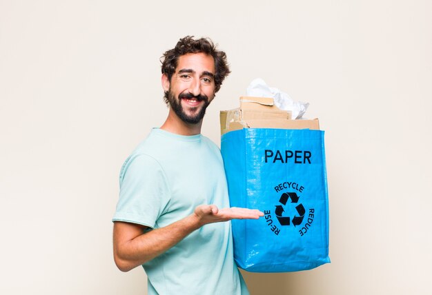 Joven sonriendo alegremente, sintiéndose feliz y mostrando un concepto en el espacio de la copia con la palma de la mano