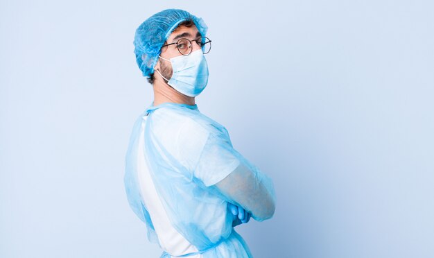 Joven sonriendo alegremente, sintiéndose feliz, satisfecho y relajado, con los brazos cruzados y mirando hacia un lado. concepto de coronavirus