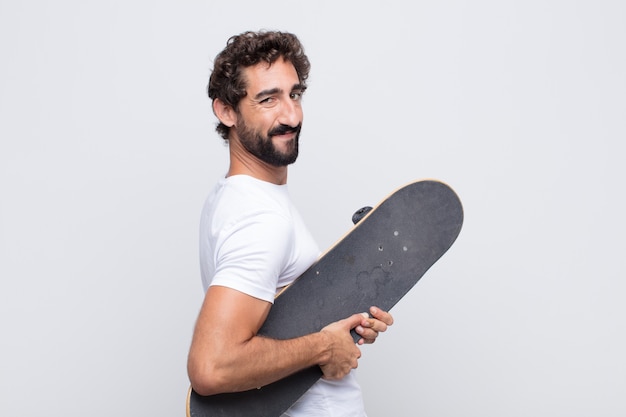 Joven sonriendo alegremente, sintiéndose feliz, satisfecho y relajado, con los brazos cruzados y mirando hacia un lado