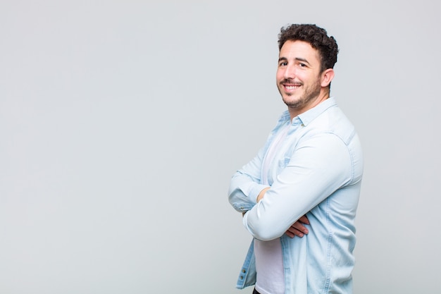 Joven sonriendo a la cámara con los brazos cruzados y un feliz, confiado