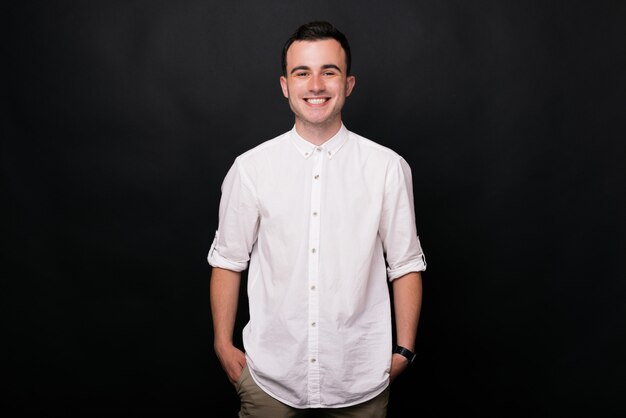 Foto un joven está sonriendo a la cámara sobre un fondo negro.