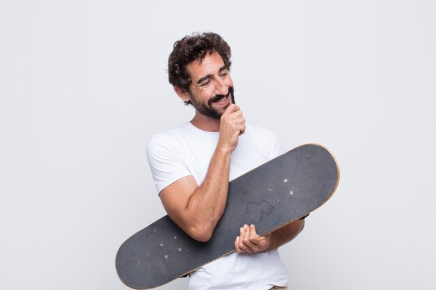 Joven sonriendo con una expresión feliz y segura con la mano en la barbilla, preguntándose y mirando hacia un lado