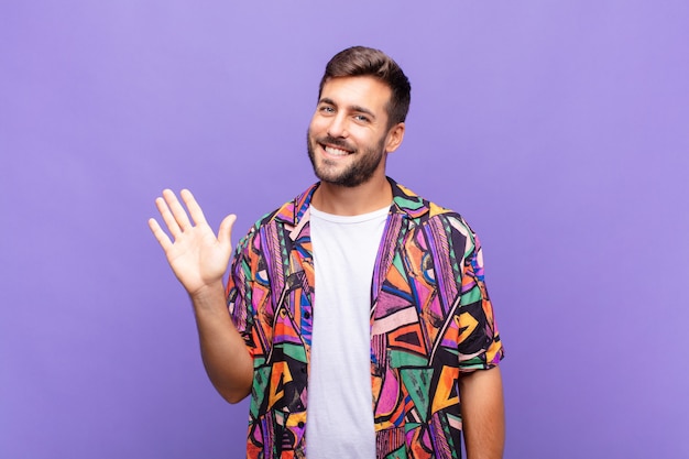 Joven sonriendo feliz y alegremente, agitando la mano aislada