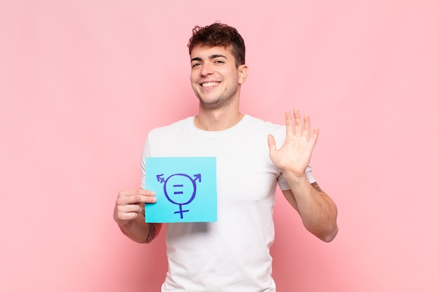 Joven sonriendo feliz y alegremente, saludando con la mano, dándote la bienvenida y saludándote, o despidiéndose