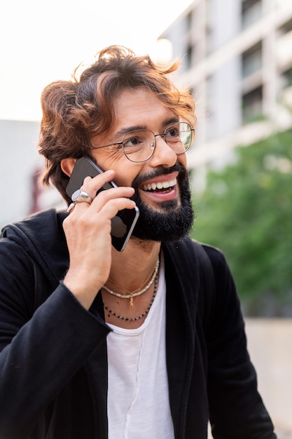 Joven sonriendo feliz hablando por teléfono móvil