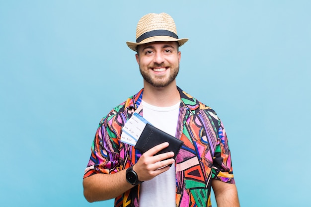 Joven sonriendo felizmente con una mano en la cadera y actitud confiada, positiva, orgullosa y amistosa