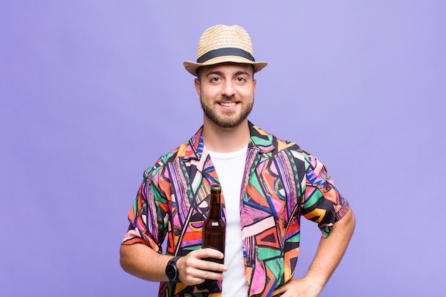 Joven sonriendo felizmente con una mano en la cadera y actitud confiada, positiva, orgullosa y amistosa