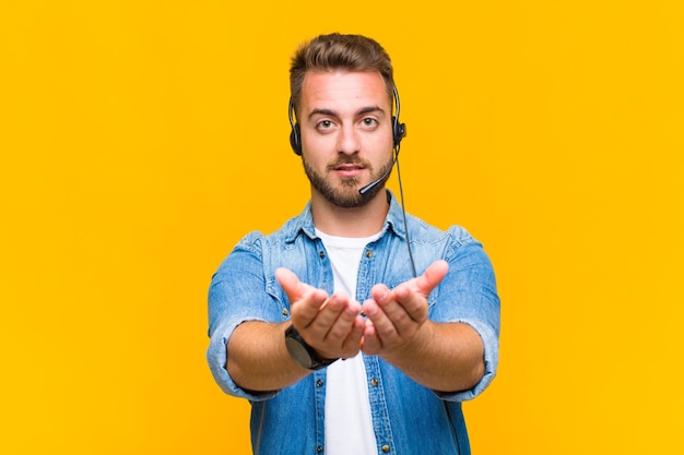 Joven sonriendo felizmente con mirada amistosa, segura y positiva, ofreciendo y mostrando un objeto o concepto