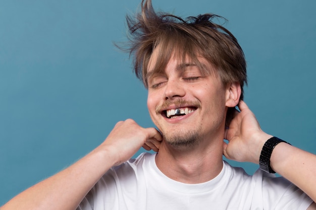 Joven sonriendo mientras tiene un diente de plata